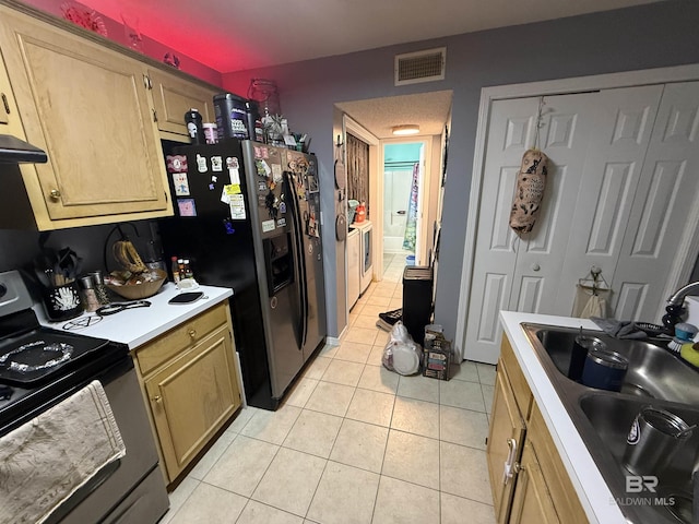 kitchen with light tile patterned floors, light countertops, visible vents, a sink, and black range