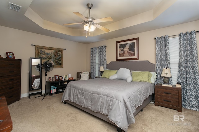 carpeted bedroom featuring a raised ceiling and ceiling fan