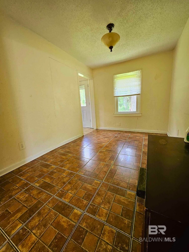 unfurnished room featuring a textured ceiling and baseboards