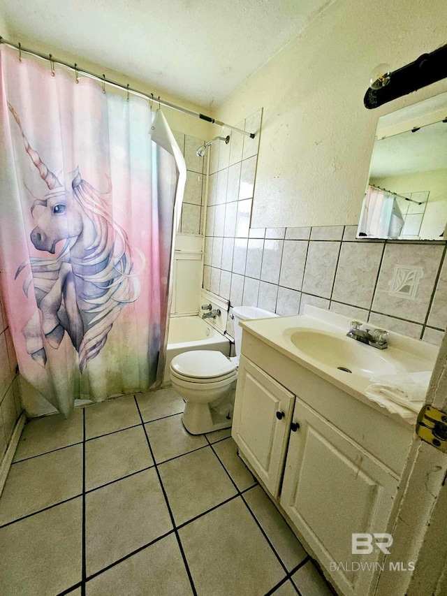 bathroom featuring tile patterned flooring, toilet, shower / tub combo with curtain, vanity, and tile walls