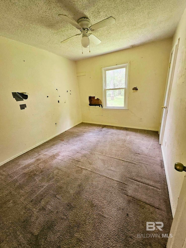 carpeted spare room featuring ceiling fan, baseboards, and a textured ceiling