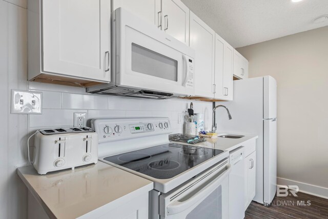 kitchen with backsplash, white appliances, dark hardwood / wood-style floors, and white cabinetry