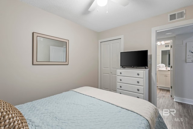 bedroom with ceiling fan, a closet, light hardwood / wood-style flooring, and a textured ceiling