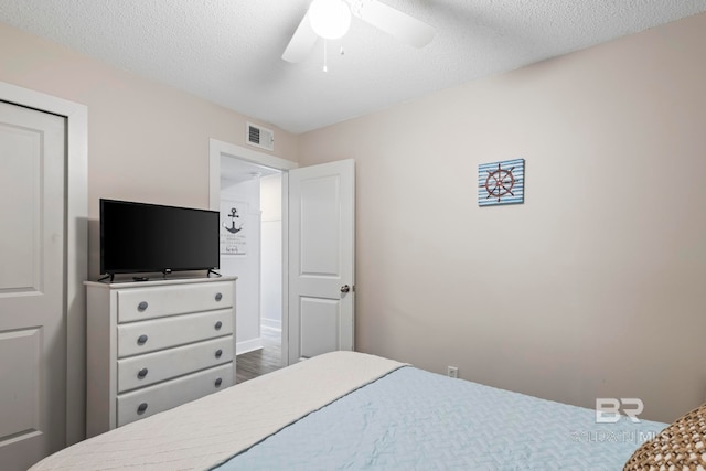 bedroom with hardwood / wood-style flooring, ceiling fan, and a textured ceiling