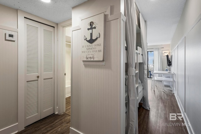 hallway with a textured ceiling and dark hardwood / wood-style floors