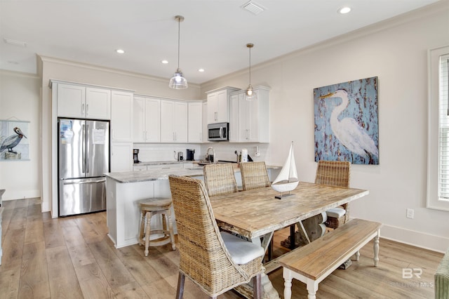 dining area featuring crown molding, light wood-style floors, and recessed lighting