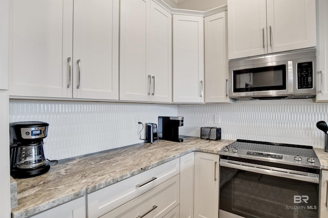 kitchen featuring appliances with stainless steel finishes, white cabinets, light stone counters, and tasteful backsplash