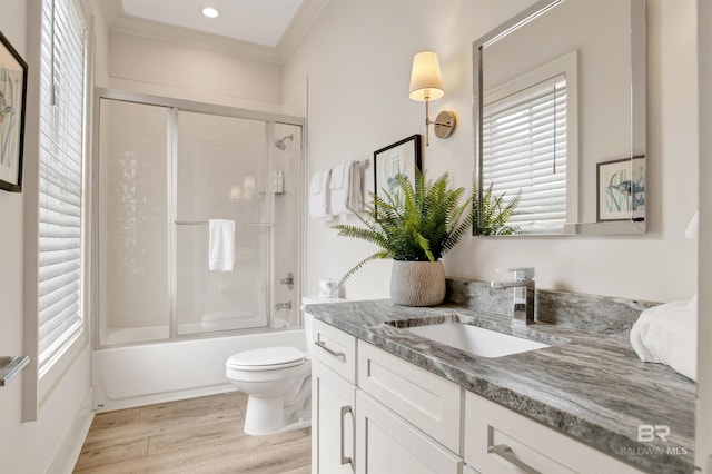 full bath featuring vanity, ornamental molding, toilet, wood finished floors, and combined bath / shower with glass door