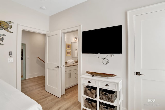 bedroom featuring light wood finished floors and ensuite bath