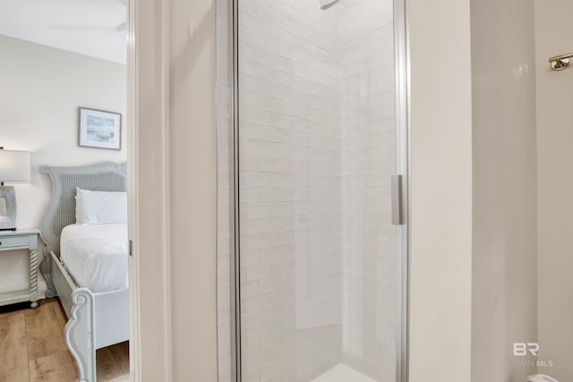 ensuite bathroom featuring a shower stall and wood finished floors