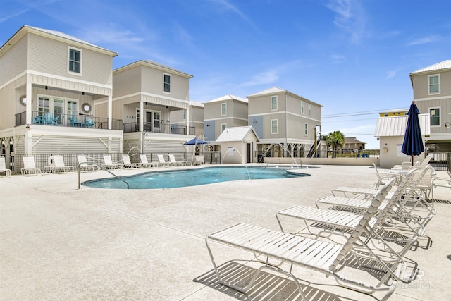 community pool with a patio area, fence, and a residential view