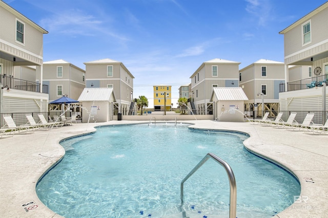 community pool with a patio area, a residential view, and fence