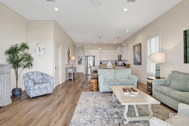 living area featuring light wood finished floors, ornamental molding, recessed lighting, and baseboards