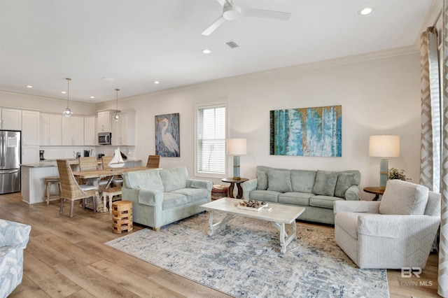 living area with crown molding, ceiling fan, recessed lighting, and light wood finished floors