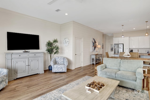 living area featuring light wood-style floors, ornamental molding, and recessed lighting