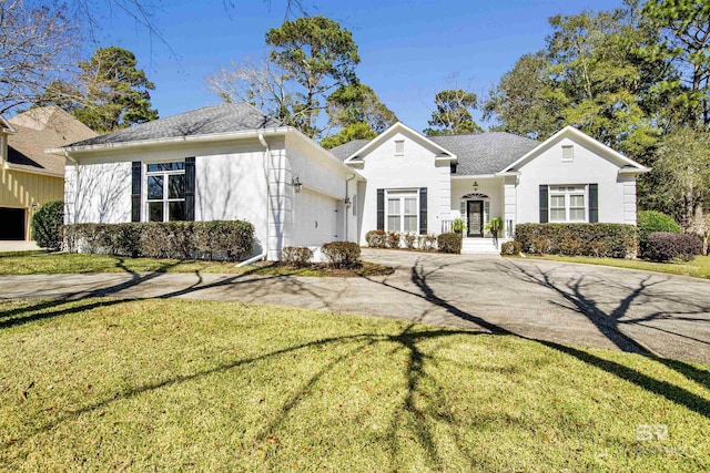 view of front of home with an attached garage, aphalt driveway, a front lawn, and stucco siding