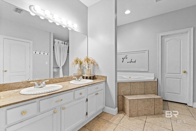 bathroom with tile patterned flooring, tiled bath, and vanity