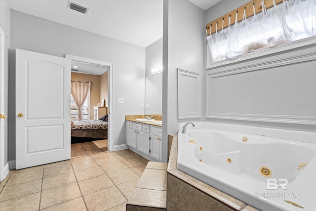 bathroom featuring tile patterned flooring, vanity, and tiled tub