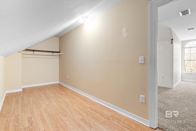 additional living space featuring lofted ceiling and light hardwood / wood-style floors