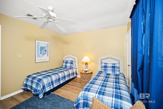 bedroom featuring hardwood / wood-style floors, a textured ceiling, and ceiling fan