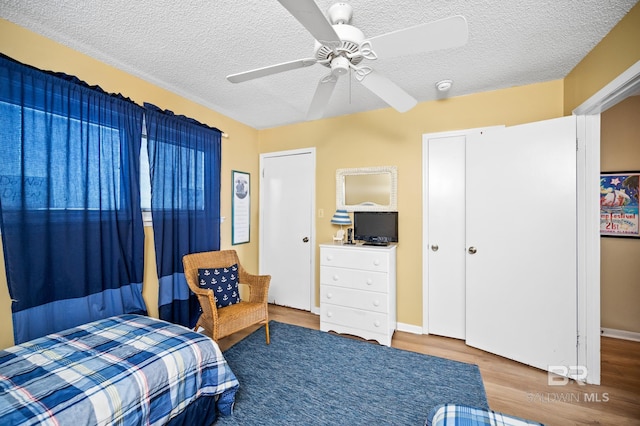 bedroom featuring hardwood / wood-style floors, a closet, a textured ceiling, and ceiling fan