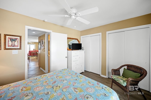 bedroom featuring ceiling fan, hardwood / wood-style flooring, and multiple closets