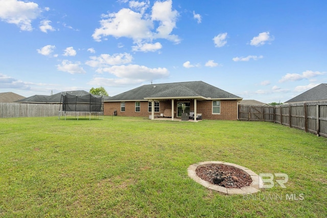 back of house featuring a trampoline, a patio area, and brick siding