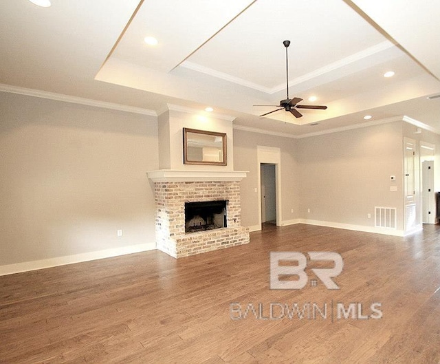 unfurnished living room with a tray ceiling, a fireplace, and hardwood / wood-style floors