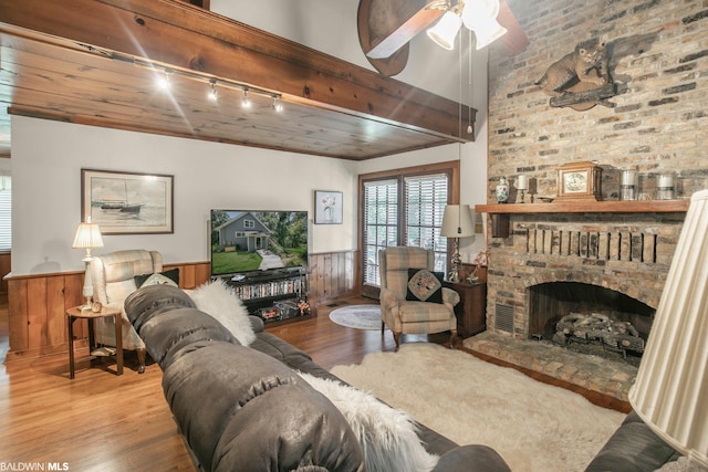 living room featuring wood-type flooring, ceiling fan, rail lighting, and a fireplace