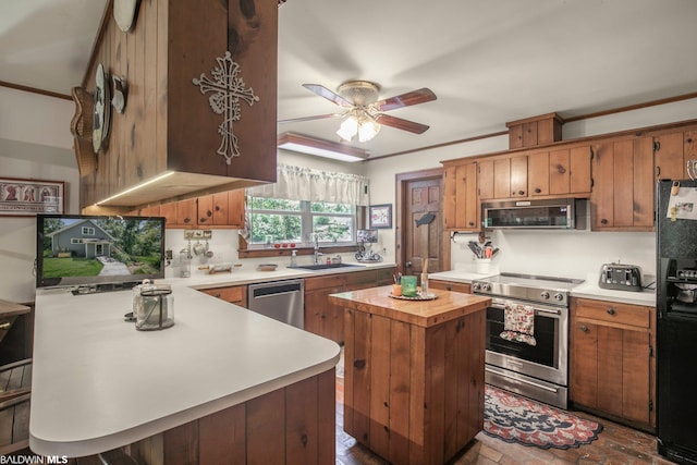 kitchen with stainless steel appliances, a center island, ceiling fan, crown molding, and sink