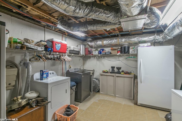 clothes washing area featuring washer and clothes dryer and light tile floors