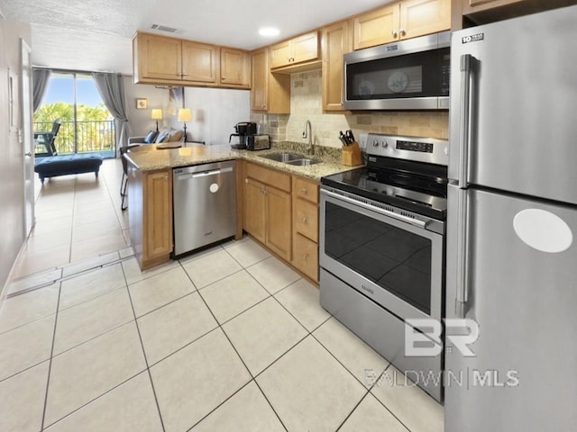 kitchen with backsplash, light tile patterned floors, light stone counters, stainless steel appliances, and a sink