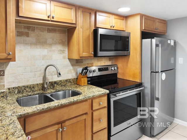 kitchen featuring backsplash, appliances with stainless steel finishes, light stone countertops, and a sink