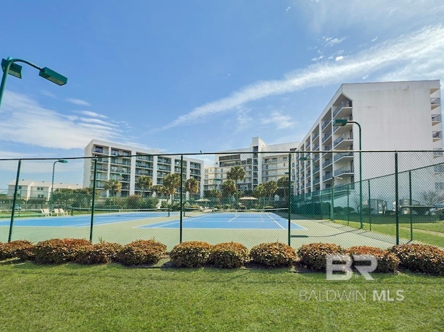 view of tennis court featuring a yard and fence