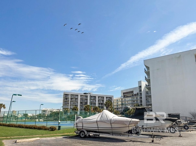 view of property's community featuring uncovered parking, a tennis court, and fence