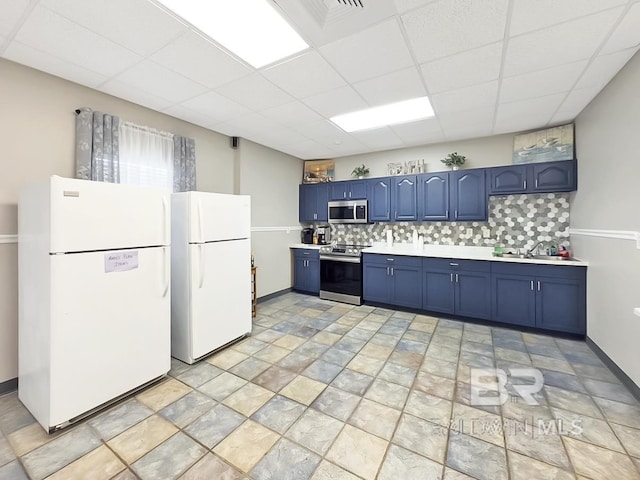 kitchen featuring blue cabinetry, a sink, stainless steel appliances, light countertops, and decorative backsplash