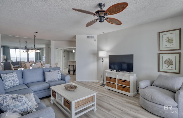24770 Perdido Beach Blvd Unit 402, Orange Beach, AL 36561 - living room featuring ceiling fan, light wood-style floors, a textured ceiling, baseboards, and a chandelier