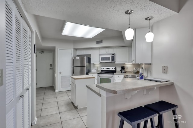24770 Perdido Beach Blvd Unit 402, Orange Beach, AL 36561 - kitchen with appliances with stainless steel finishes, a kitchen island, a peninsula, light countertops, and white cabinetry