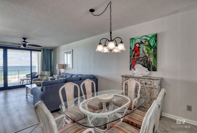 24770 Perdido Beach Blvd Unit 402, Orange Beach, AL 36561 - dining space with a textured ceiling, a chandelier, a ceiling fan, a water view, and baseboards