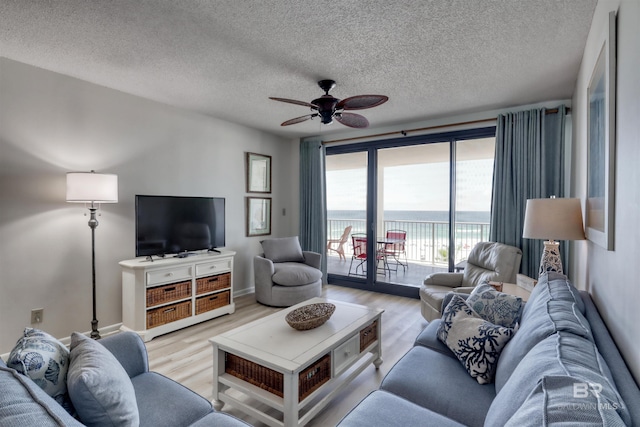 24770 Perdido Beach Blvd Unit 402, Orange Beach, AL 36561 - living room featuring light wood-type flooring, a ceiling fan, a textured ceiling, and baseboards