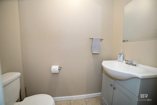 bathroom with toilet, vanity, tile patterned floors, and baseboards