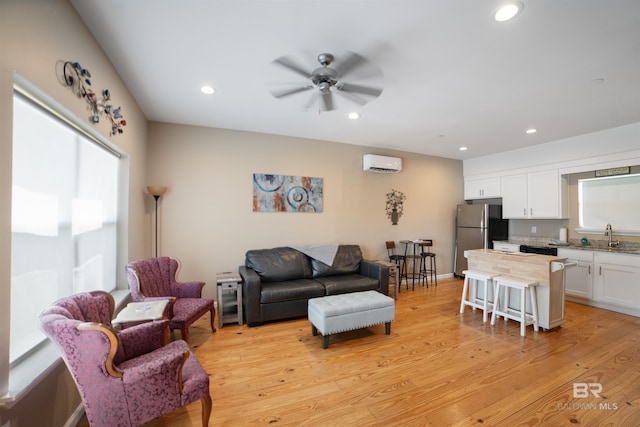 living area with recessed lighting, light wood-style flooring, an AC wall unit, and a ceiling fan