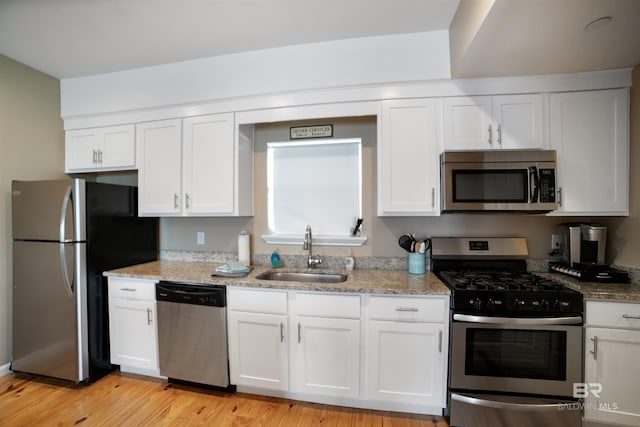 kitchen with a sink, white cabinetry, light stone countertops, and appliances with stainless steel finishes