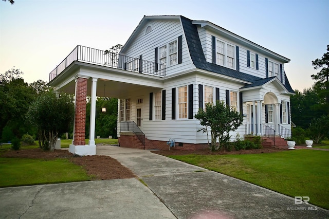 view of front of property with a lawn and a balcony