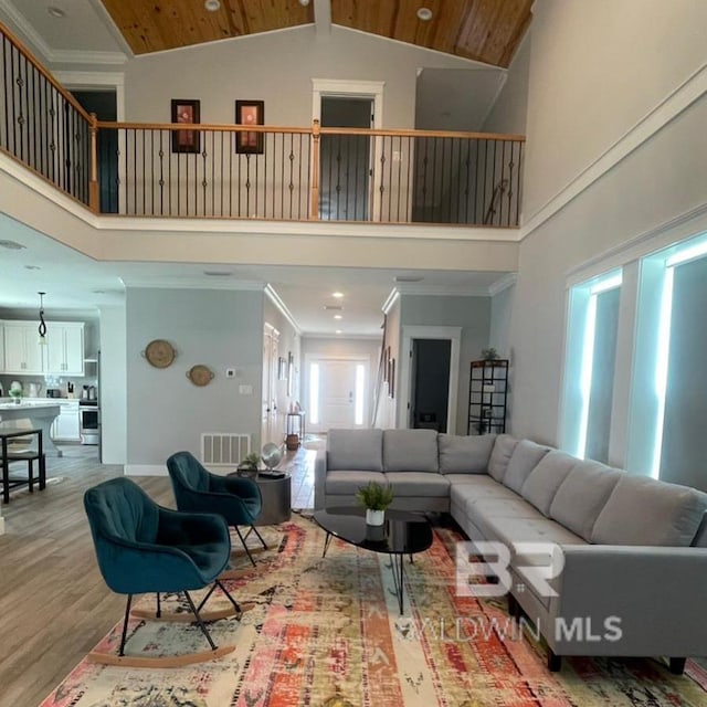 living room featuring hardwood / wood-style flooring, ornamental molding, and high vaulted ceiling