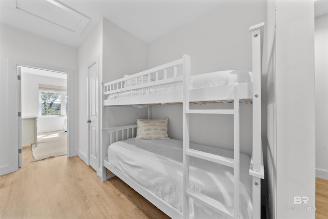 bedroom featuring attic access, baseboards, and wood finished floors