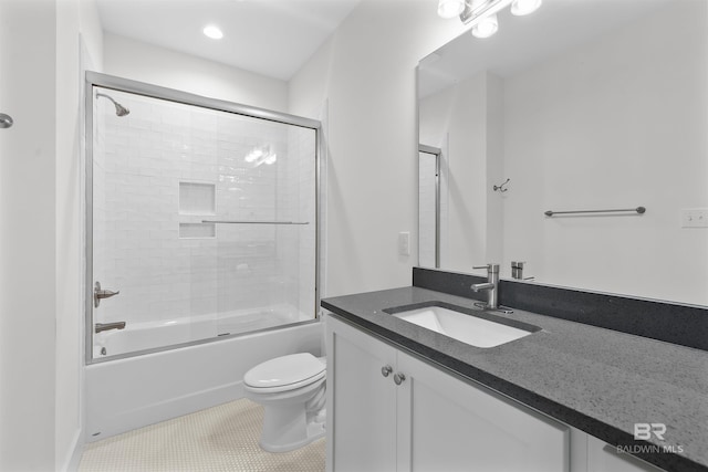 bathroom featuring toilet, vanity, bath / shower combo with glass door, and tile patterned floors