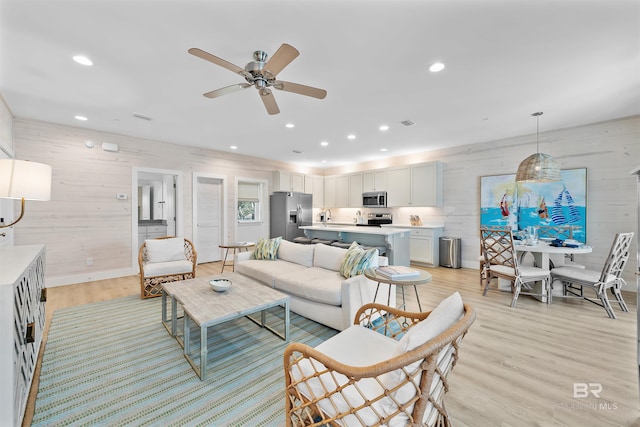 living area featuring wood walls, recessed lighting, visible vents, and light wood-style floors