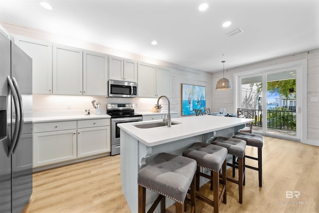 kitchen with stainless steel appliances, pendant lighting, light countertops, and a kitchen bar