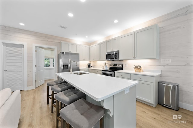 kitchen featuring a sink, a kitchen breakfast bar, light countertops, appliances with stainless steel finishes, and an island with sink